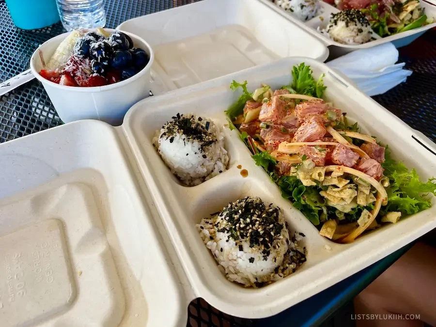 A disposable container with fresh, raw fish and a bowl of rice.