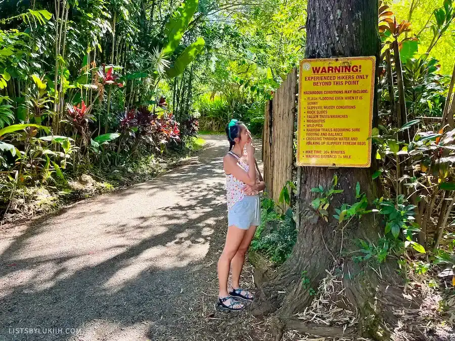 A woman standing on a trail looking at a sign warning about bugs.