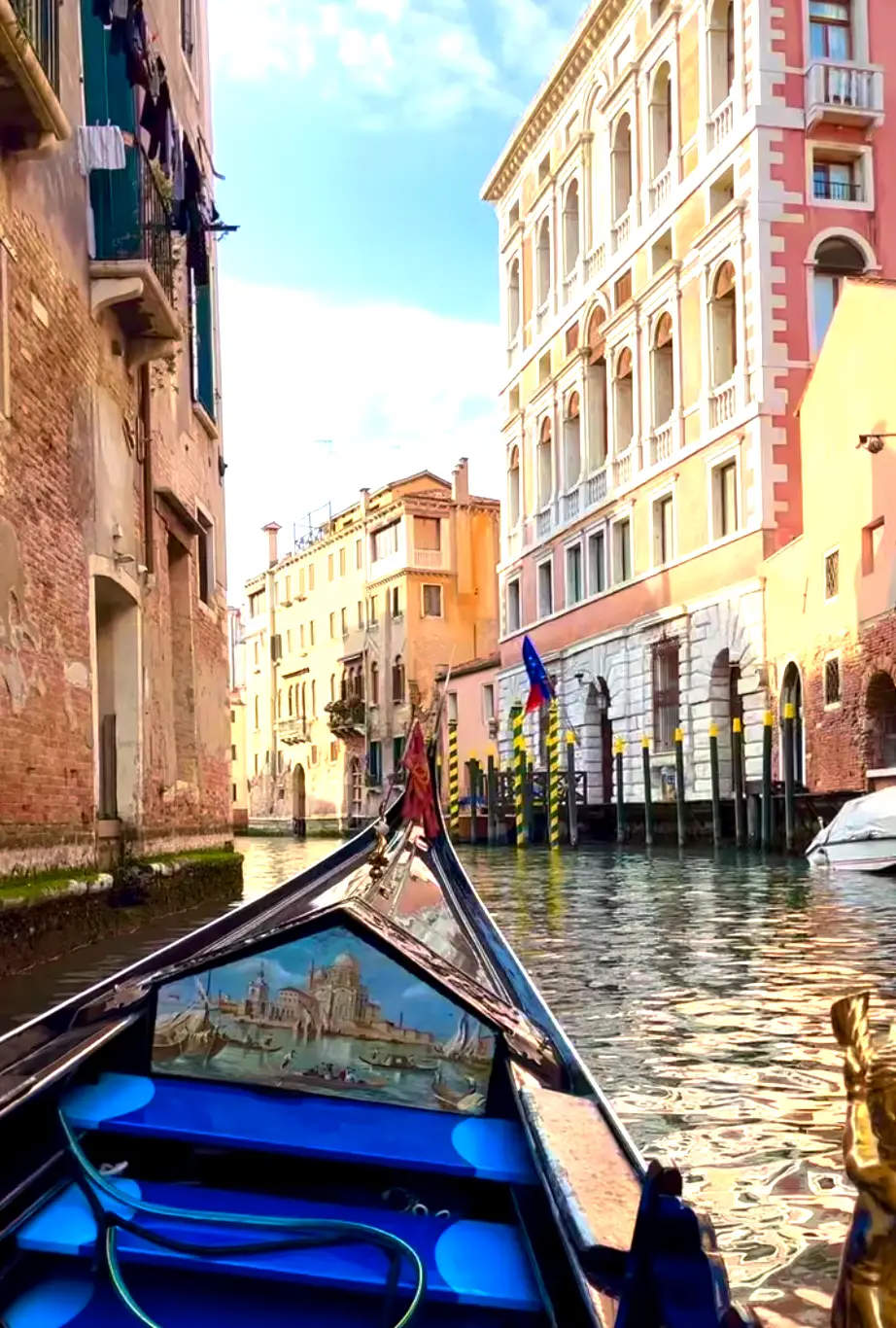 The front of a blue boat floating on a small canal near sunset time.