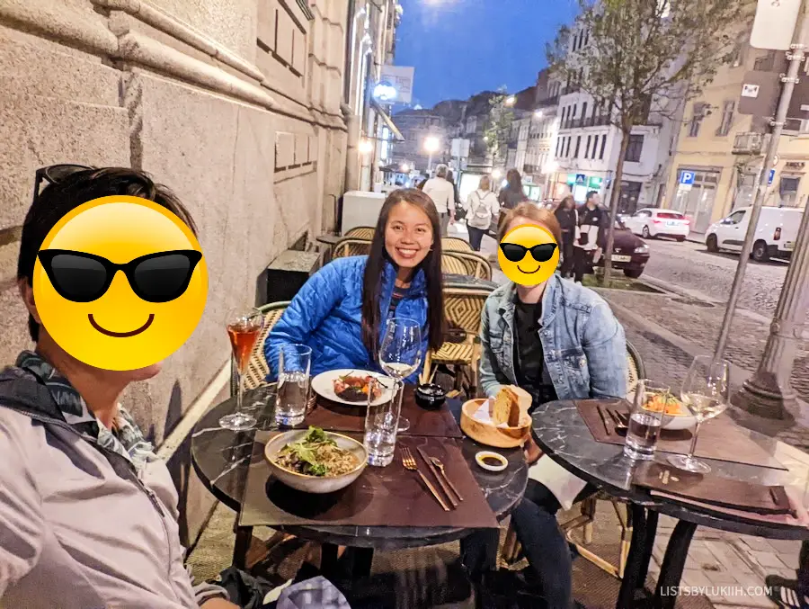 Three women dining outside on the side of a street.