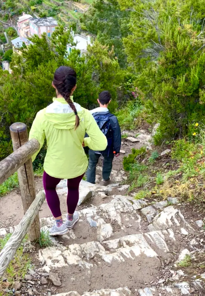 Two people climbing down a steep set of stairs down a mountain.