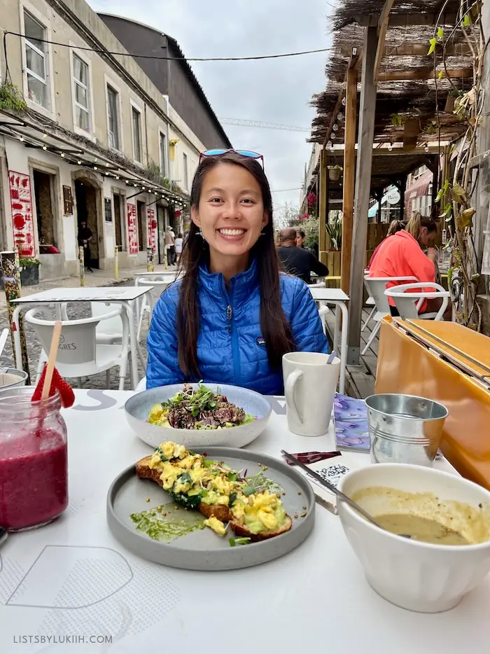 A woman sitting outside in a pedestrian-friendly street while having a meal.