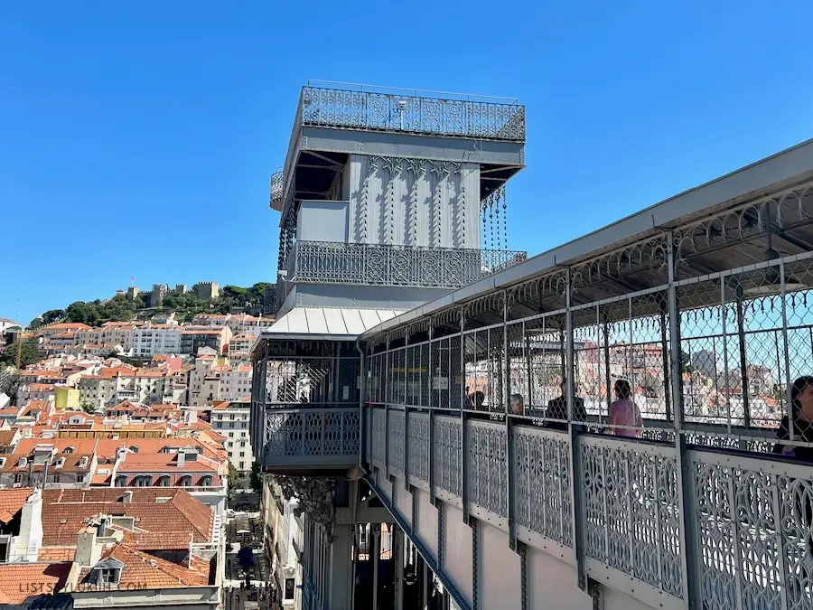 An intricate, gray elevator against a background of orange rooftops.