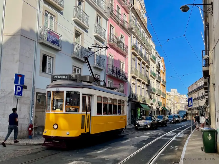 A yellow tram on a narrow European street.