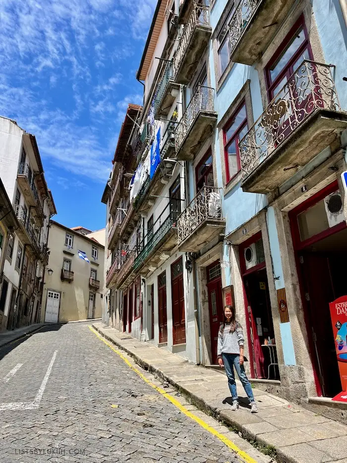 A woman standing on a hill in a narrow street with colorful buildings.