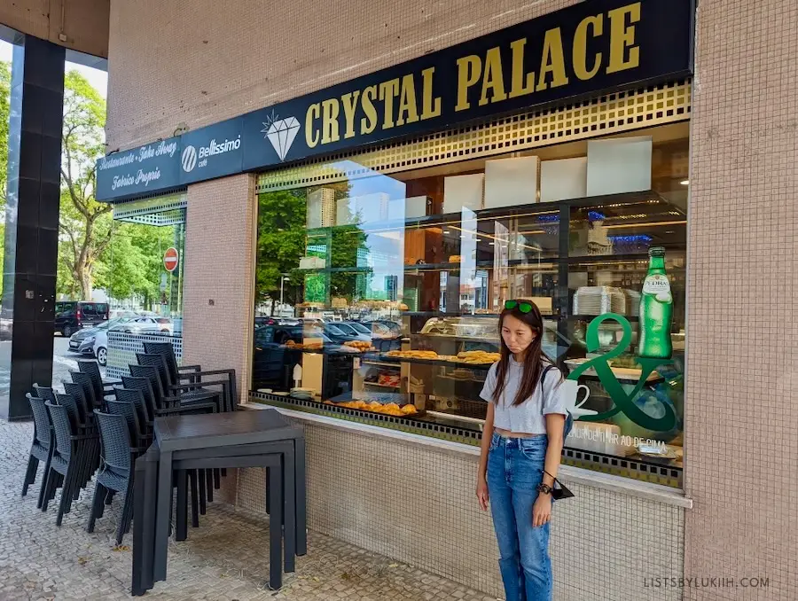 A woman looking sad in front of a bakery with the sign, Crystal Palace.