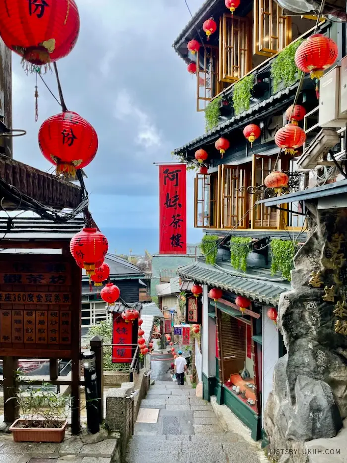 A view of a narrow street with staircase flanked by lantern-decorated buildings.