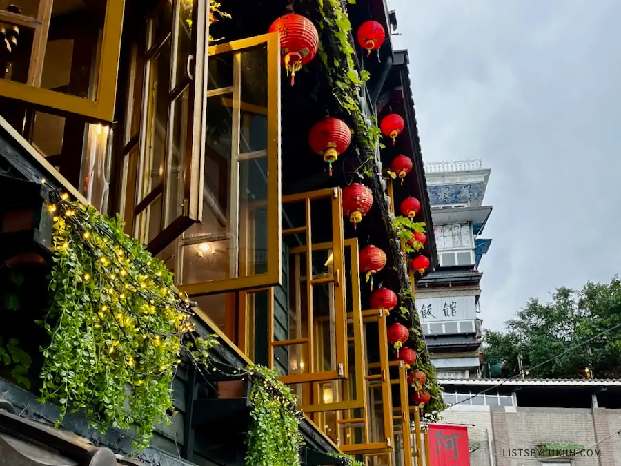 A set of windows decorated with green plants and red lanterns.