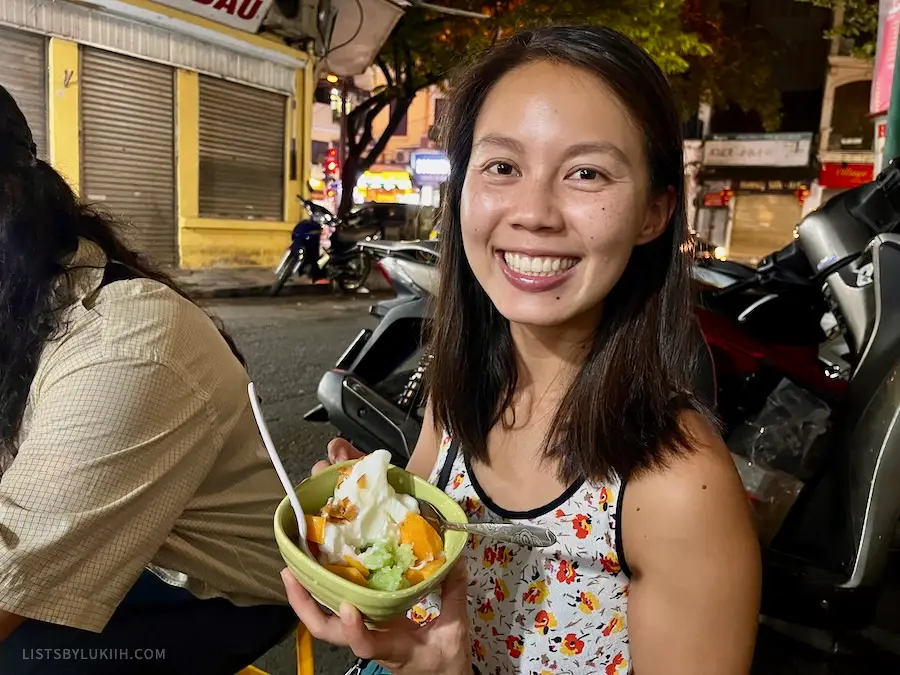A woman holding ice cream with chunks of fruit in them.