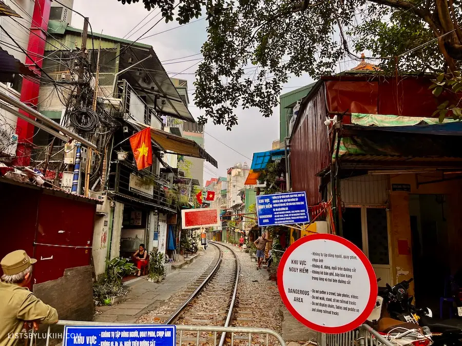 Train tracks running through a street of closely-placed buildings.