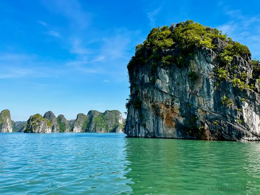 A limestone cliff jutting out of emerald water.