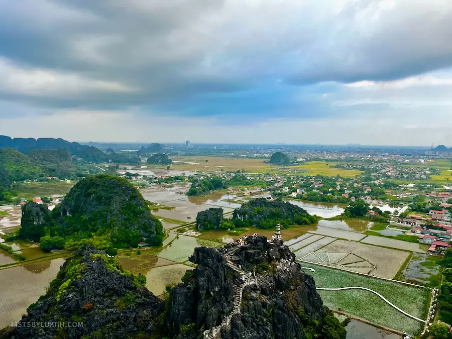 A high view of small green mountains surrounded by water fields.