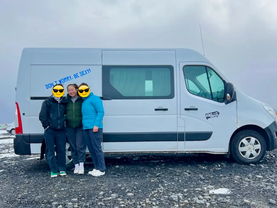 Three people standing next to a campervan .