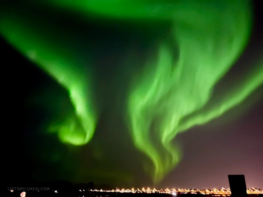 Green lights in the sky over a city at night.