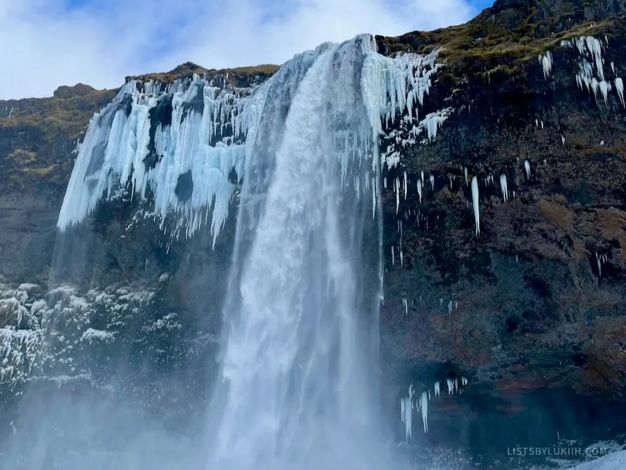 A large waterfall in the winter falling out of an icy mountain.