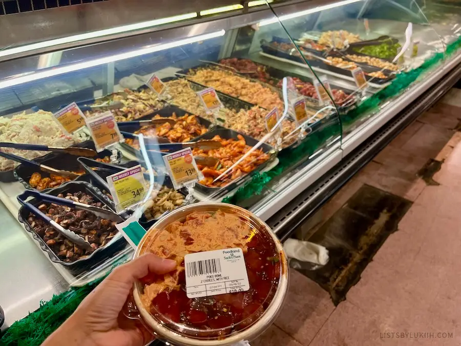 A bowl of marinated raw fish with lots of other food selection in the background.