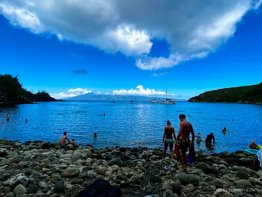 A bay with people entering it while stepping on rocks.