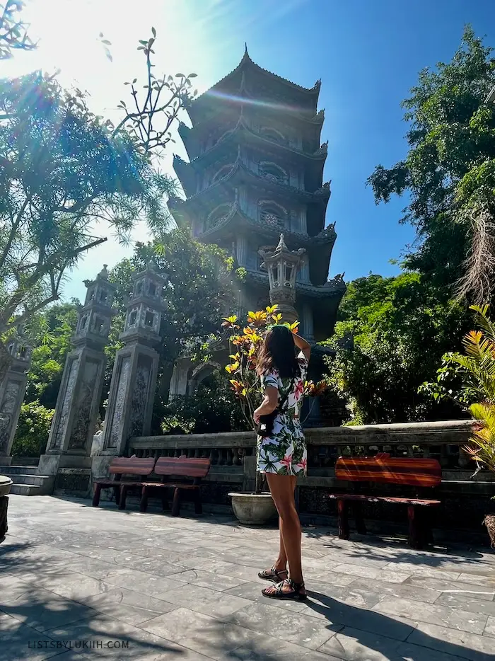 A woman staring up at a tall pagoda.