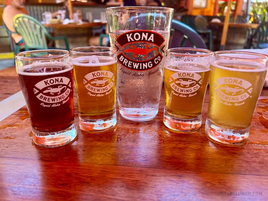 Five glasses with beer with Kona Brewery Co branding on them.
