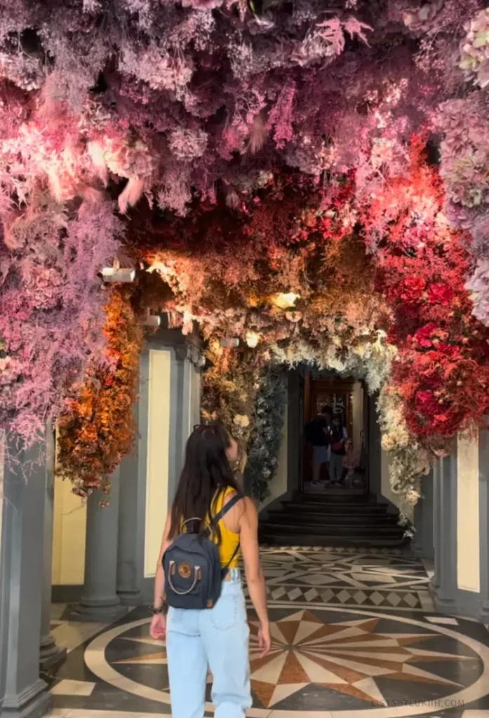 A woman entering a hall with a ceiling decorated in flowers.