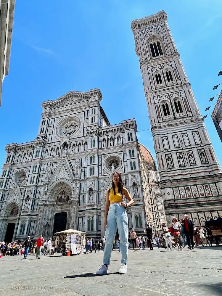 A woman standing in front of a white, intricate church.