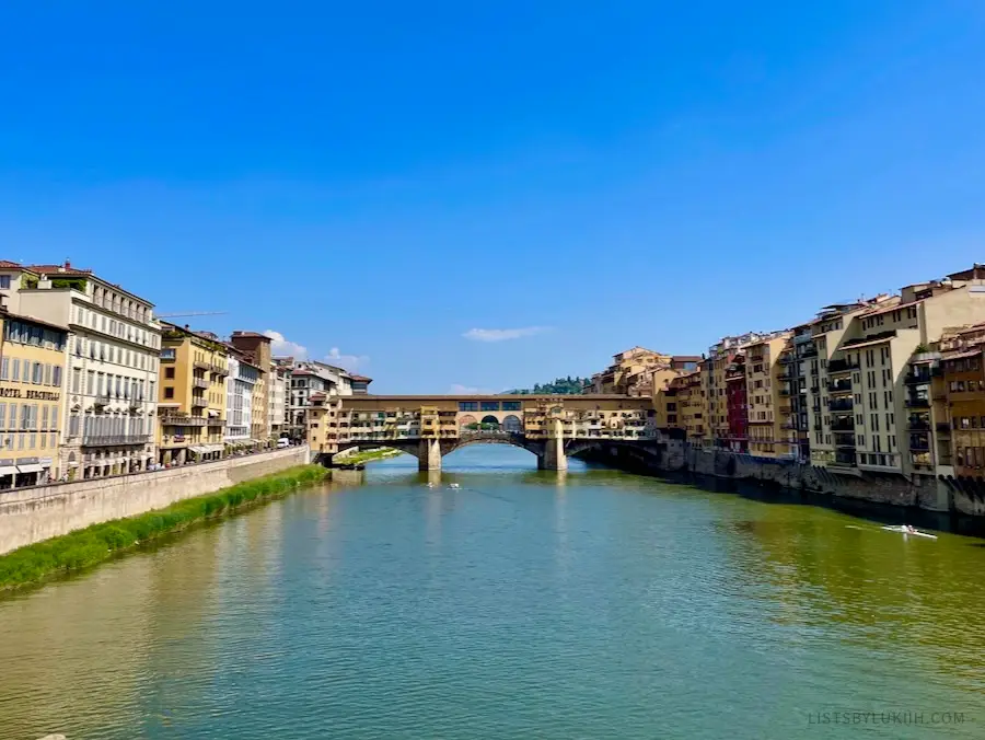 An old bridge running across a narrow canal, flanked by flat, short buildings on both sides.