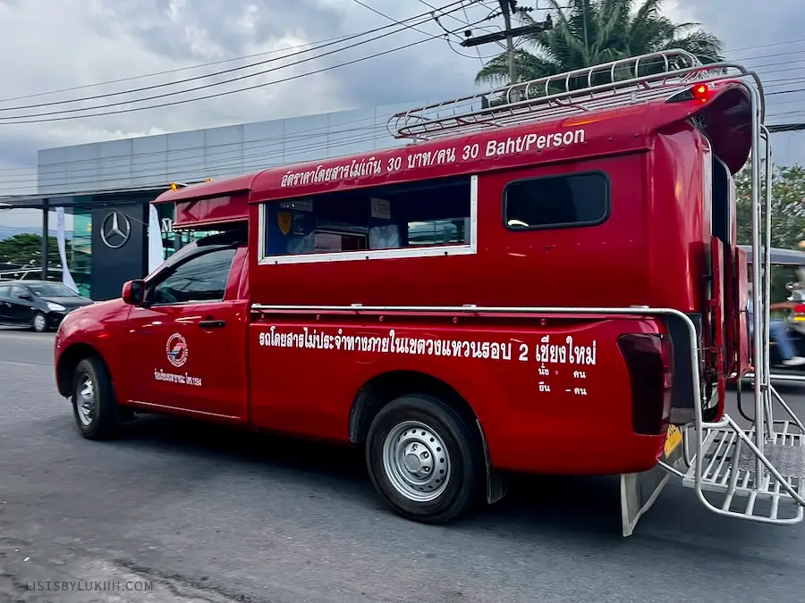A red truck with Thai on it saying that it's local transportation.
