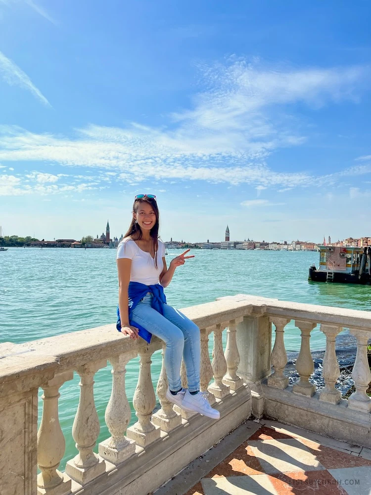 A woman sitting on a ledge next to a bit canal.