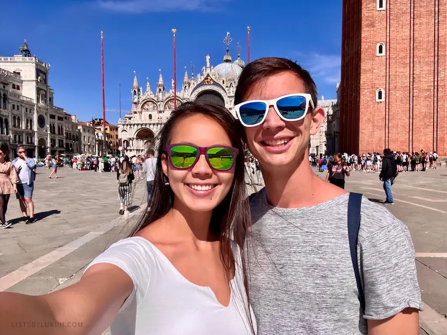 Two people taking a selfie with an ornate building behind them.