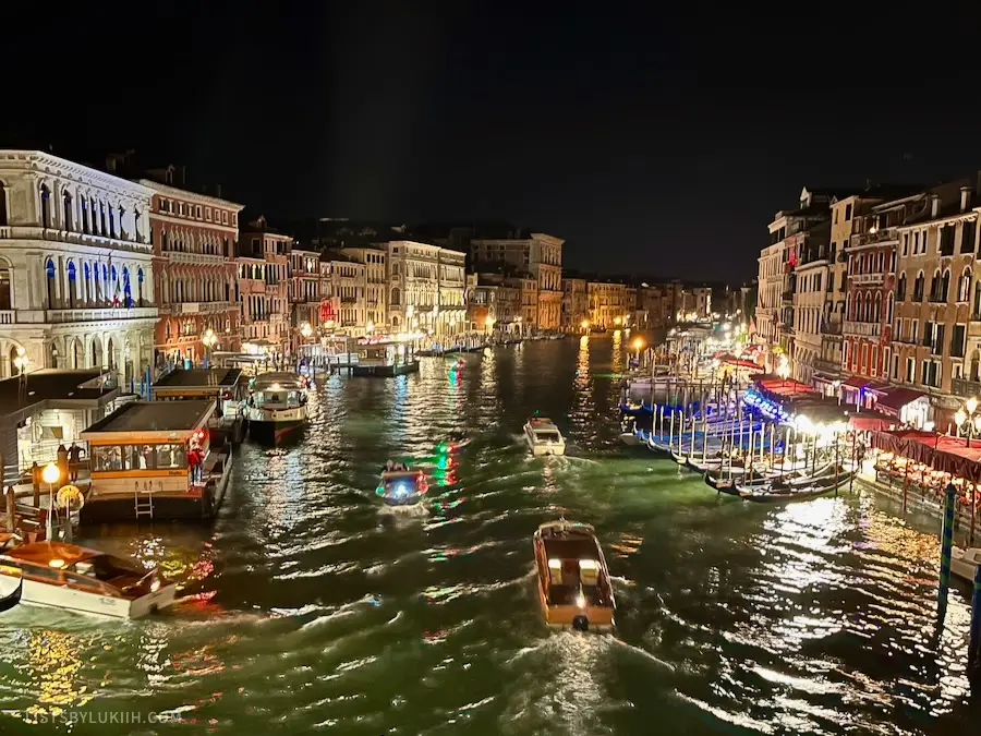 A big canal with boats and lights at night.