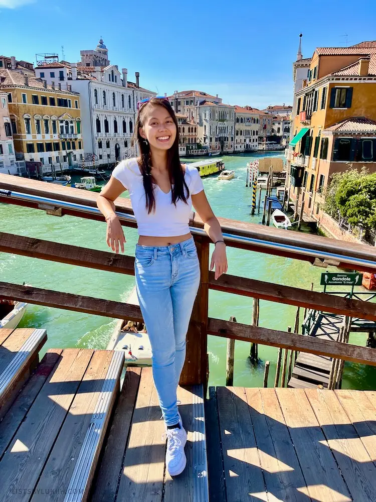 A woman standing on a wooden staircase overlooking a canal.