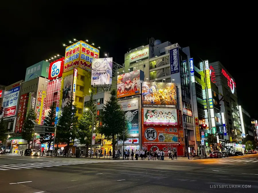A set of lit-up buildings with anime girls on it.
