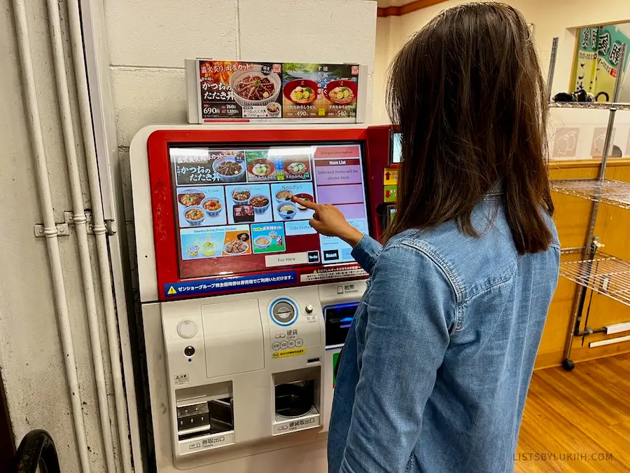 A woman pushing buttons on a screen with food selections on it.