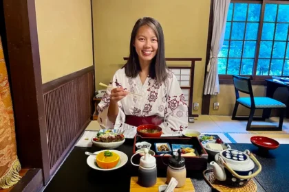 A woman holding chopsticks with little plates of foot in front of her.