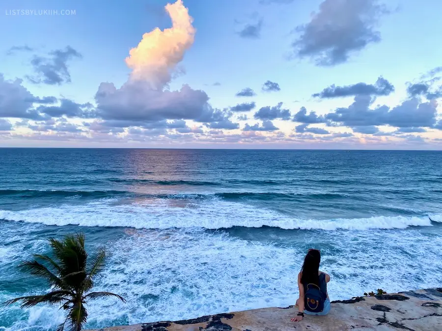 A woman sitting and looking out at the ocean.