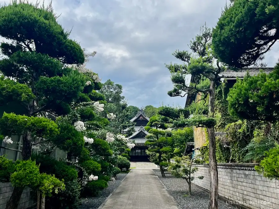 A Japanese temple hidden by some lush trees.