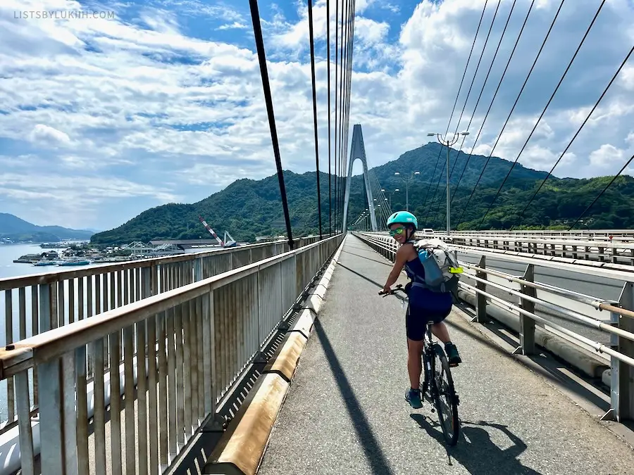 A woman biking on a modern-looking bridge.
