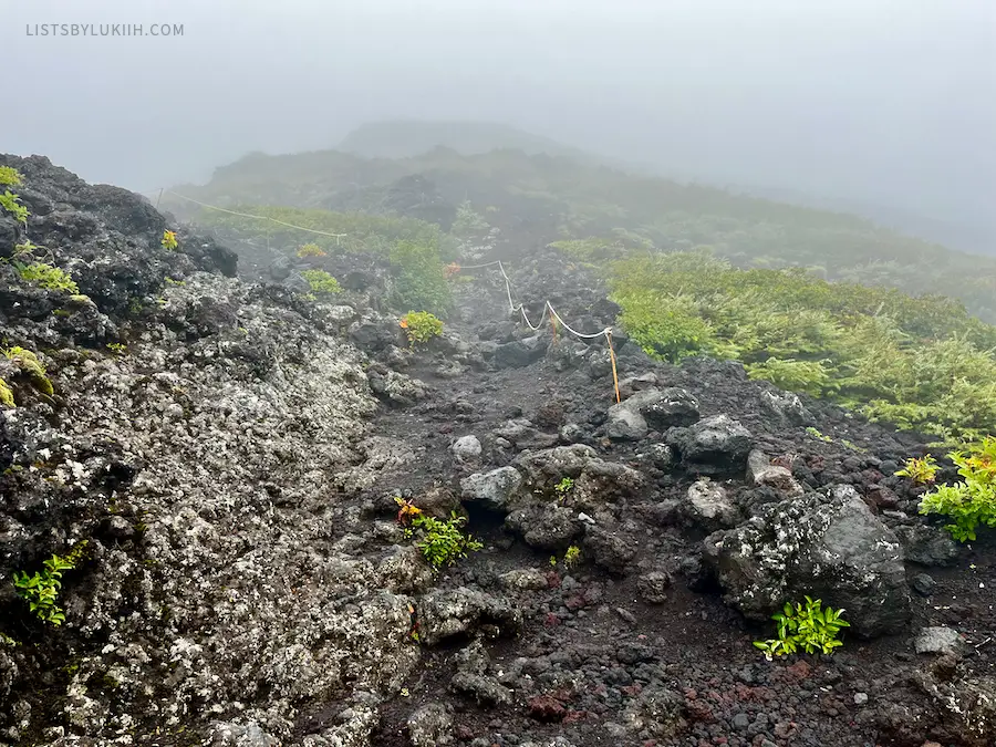 Rocky volcanic terrain trail in thick fog.