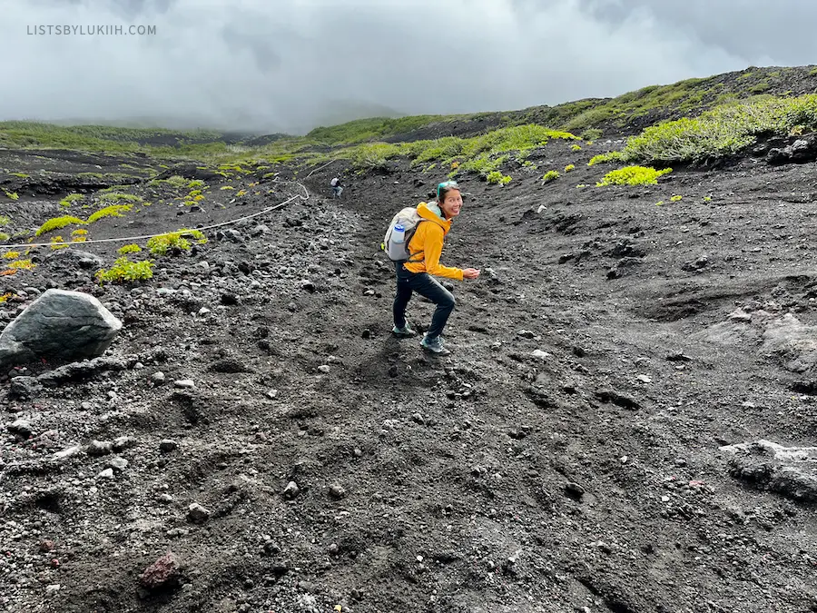 A hiker going down steep volcanic gravel.