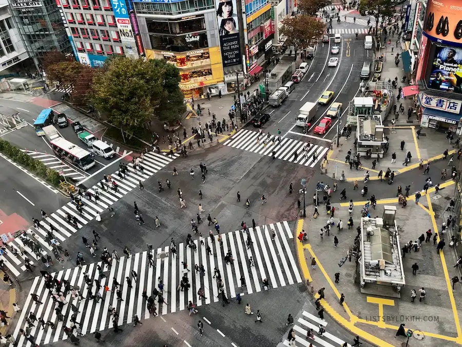 A large intersection with many pedestrians walking on it.