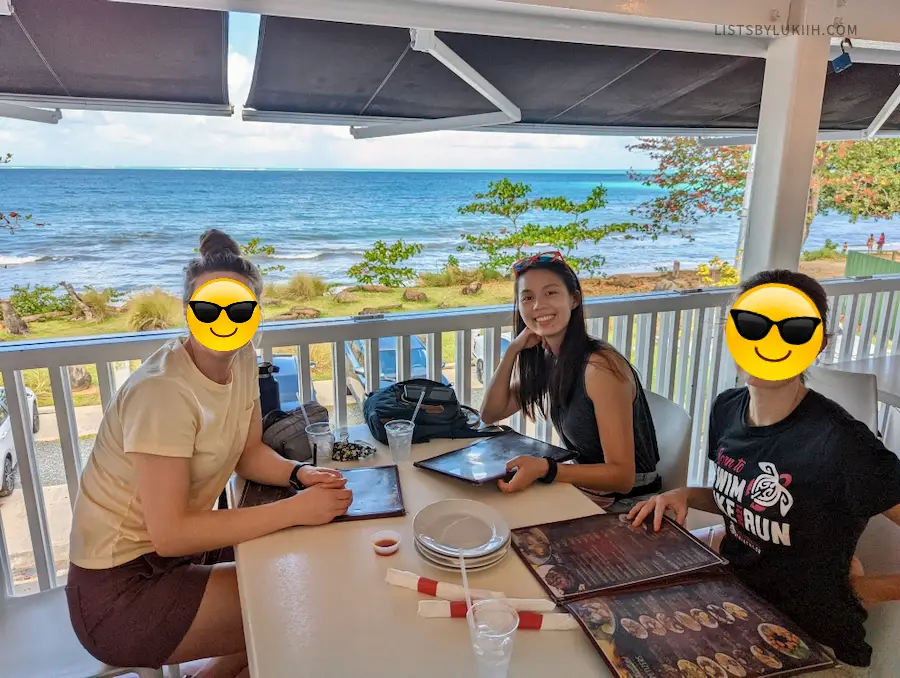 Three women sitting around a restaurant table overlooking a beautiful ocean view.