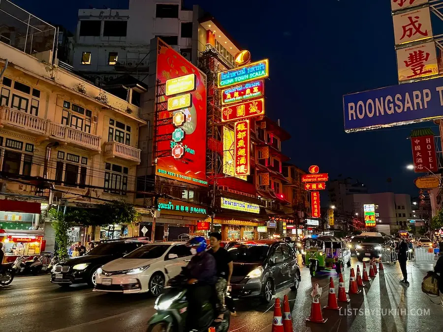 A busy street with lit-up signs with Chinese writing.