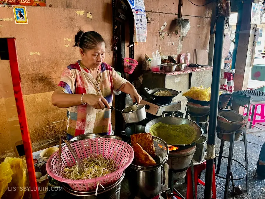 A woman cooking at an outdoor street kitchen.