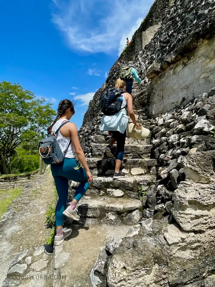 Three people walk up the uneven and stone steps of ancient ruins.