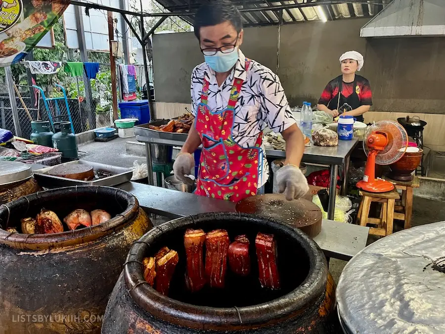 A man checking in on pork belly hung around a cylinder cooking case.