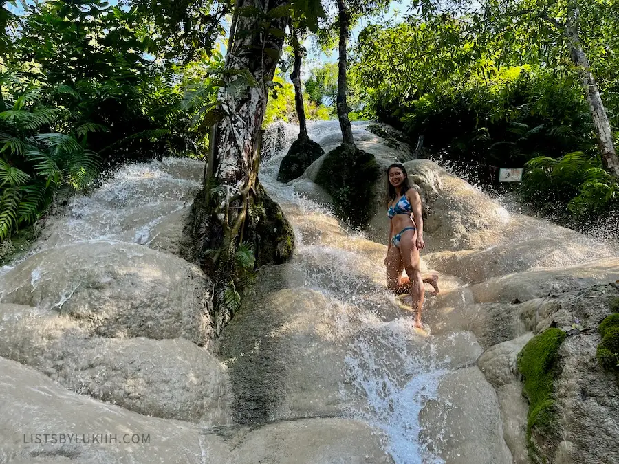 A woman standing on a waterfall with moving water.