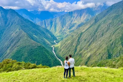 Two people standing and facing a vast valley.
