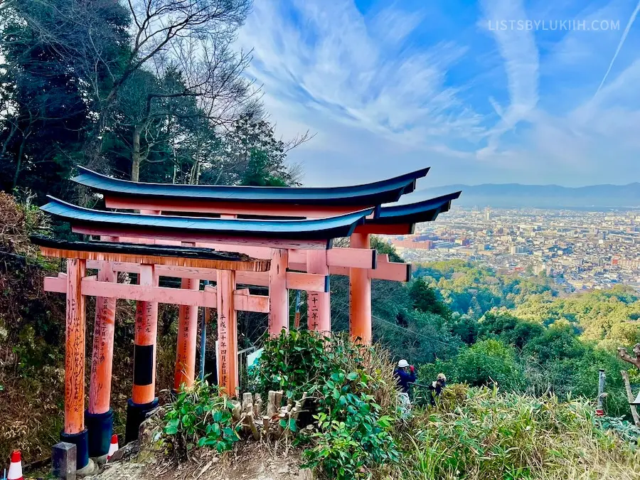 A view of red shrines overlooking a city.