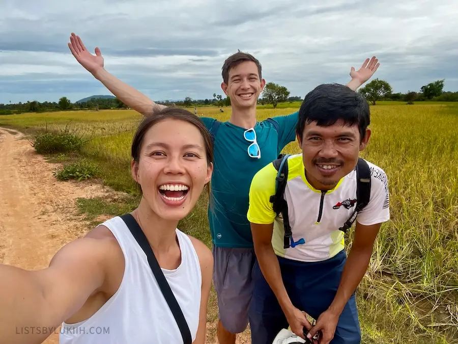 Three people posing for a selfie with rice fields in the background.