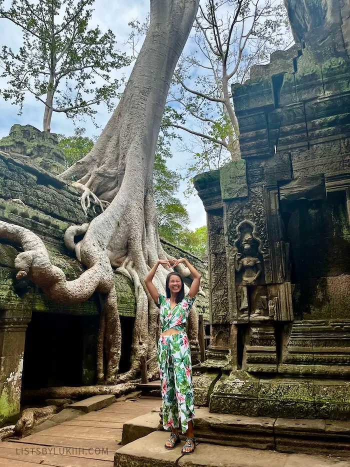 The woman posing in front of a big tree growing out of Cambodian ruins.